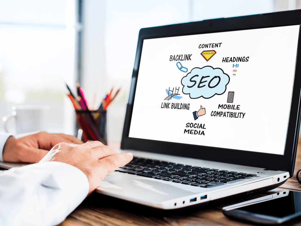 Tela de notebook exibe conceitos como backlinks, headings, conteúdo e compatibilidade móvel relacionados ao SEO.