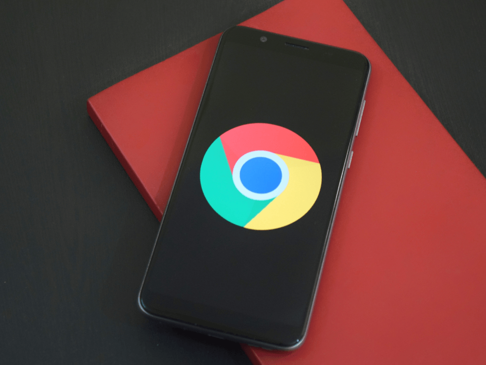 Smartphone exibindo o navegador Chrome sobre uma superfície, representando o acesso a sites e pesquisas pela internet.