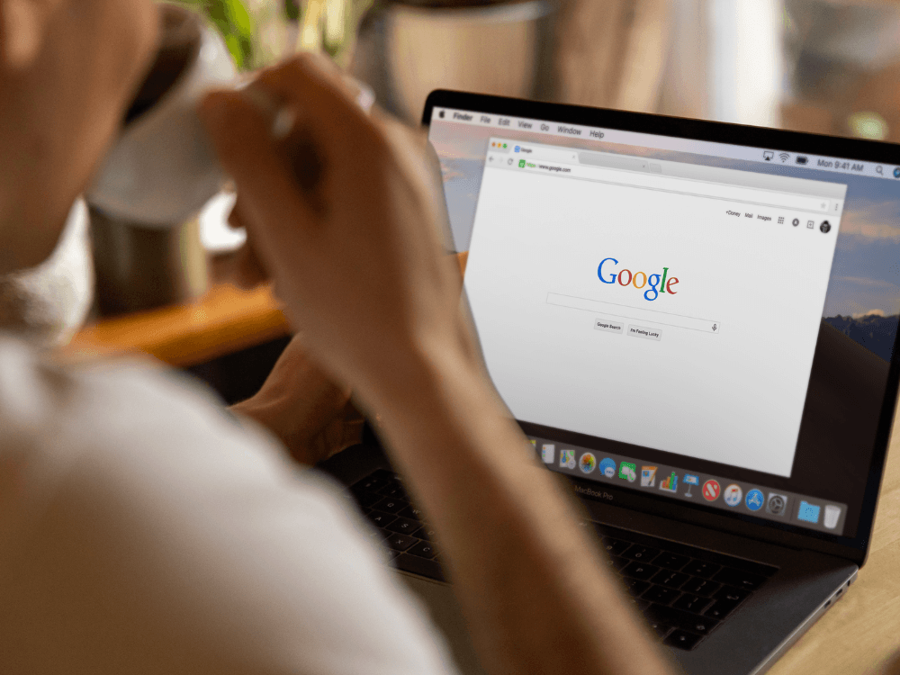 Pessoa utiliza notebook com a página inicial do Google aberta, representando a busca online por empresas e serviços. Tudo para explicar como melhorar posicionamento no google