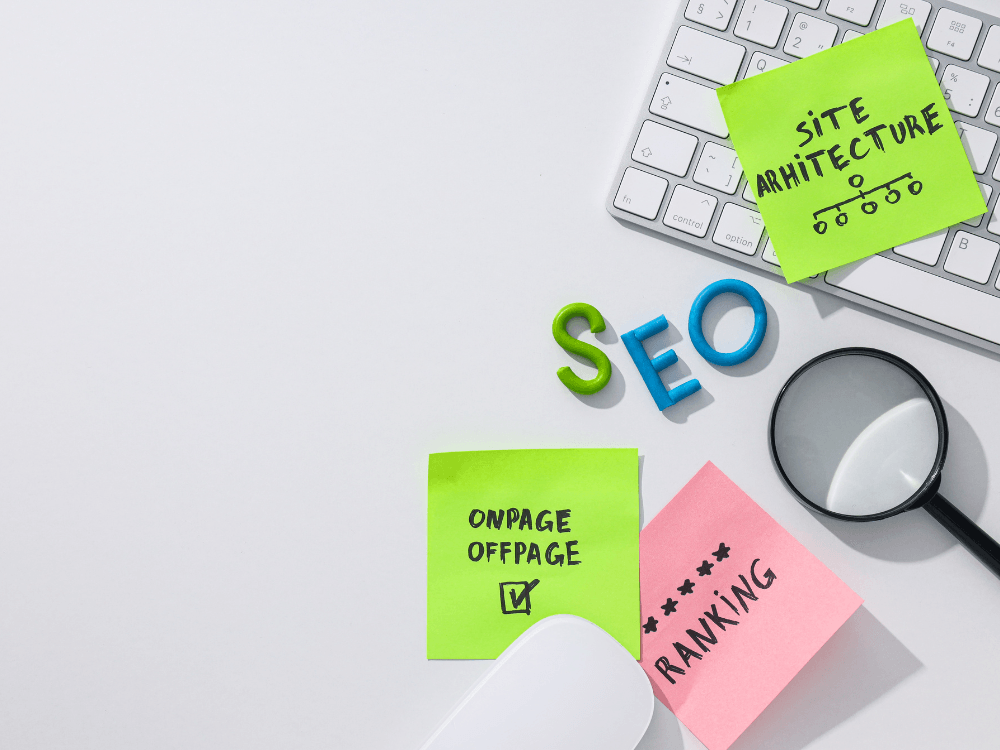 Mesa com teclado, lupa e notas sobre SEO, arquitetura de site, otimização on-page e ranking nos resultados de busca.