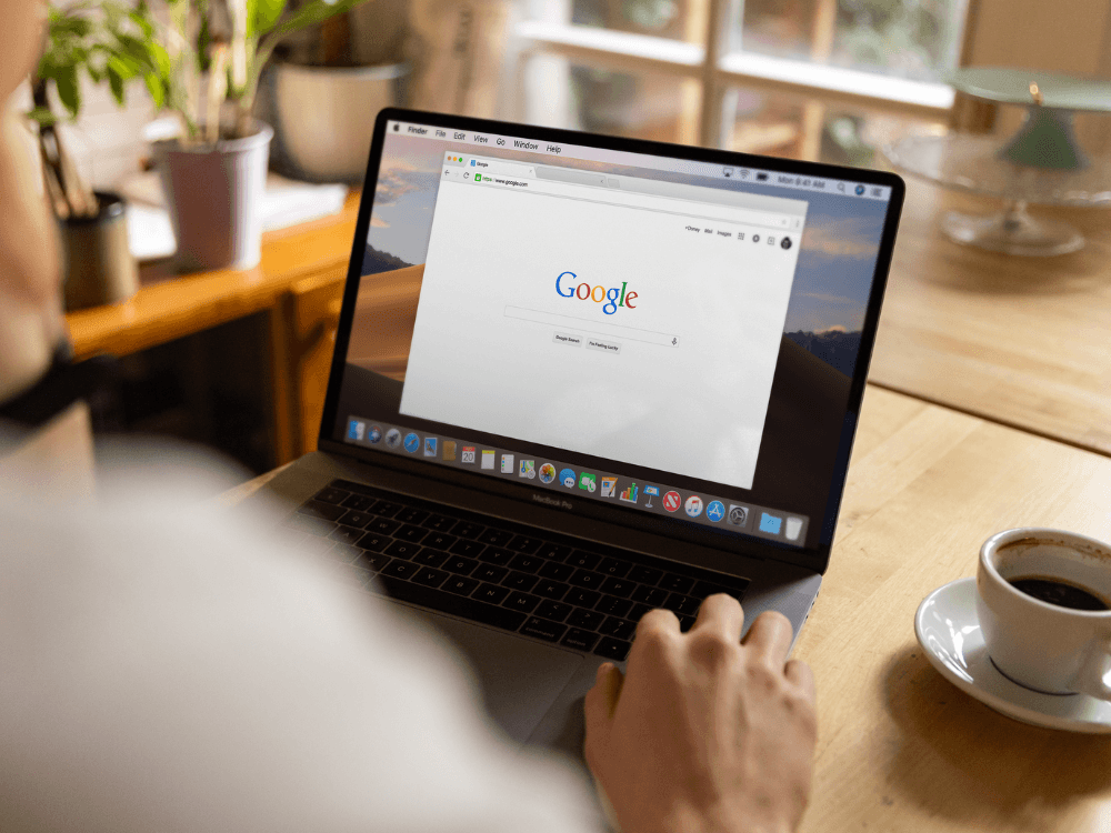 Pessoa utilizando notebook com a página inicial do Google aberta, representando a busca por informações e os resultados da SERP. Tudo para explicar o que é SERP.